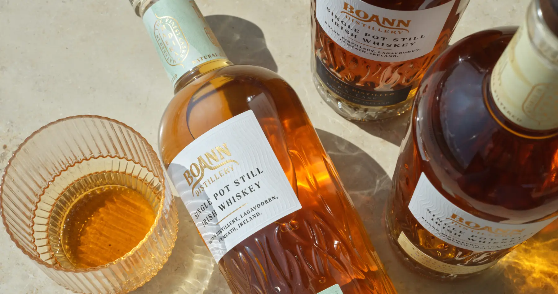 three bottles of single pot still whiskey with glass